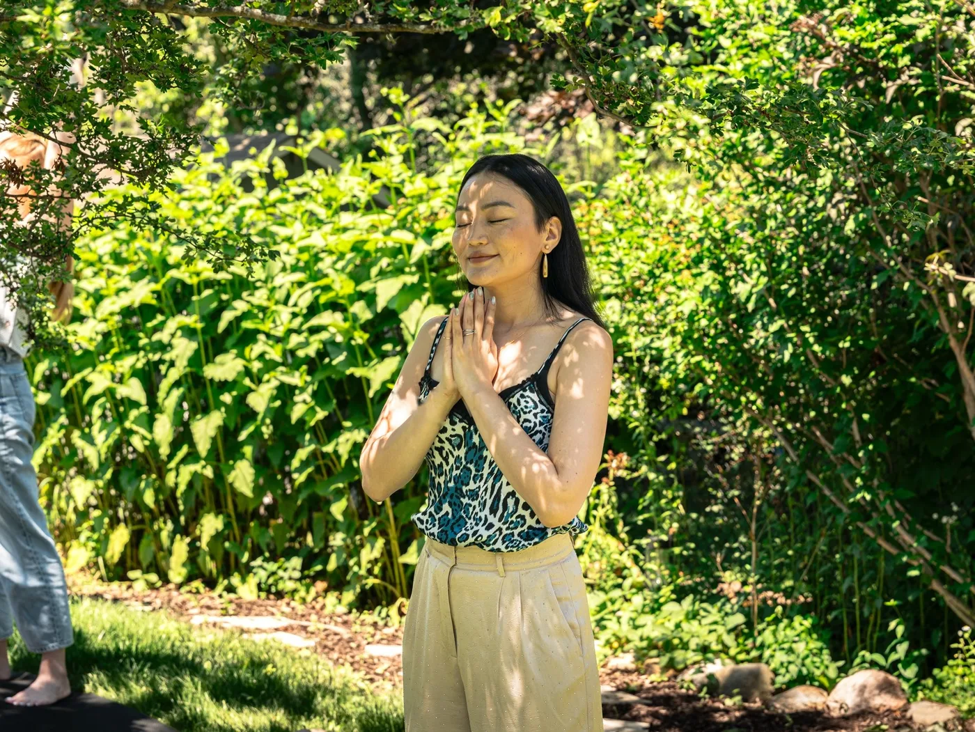 Nomin in her garden with her hands on her heart